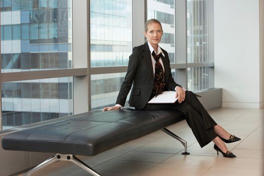 Full length portrait of a businesswoman sitting in office lobby
