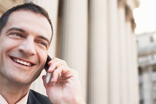 Closeup of happy businessman using cell phone outdoors