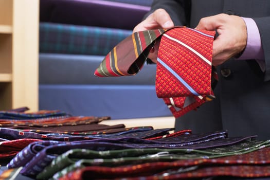 Closeup midsection of a businessman selecting ties in clothes store