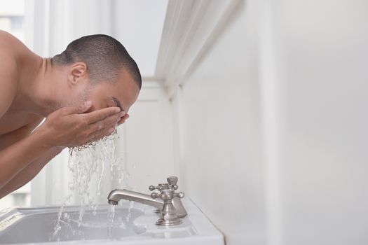 Middle aged man washing his face in sink