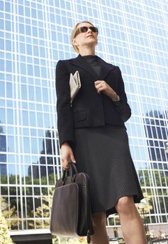 Low angle view of businesswoman with bag and newspaper