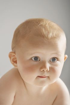 Closeup of cute baby looking away isolated on gray background