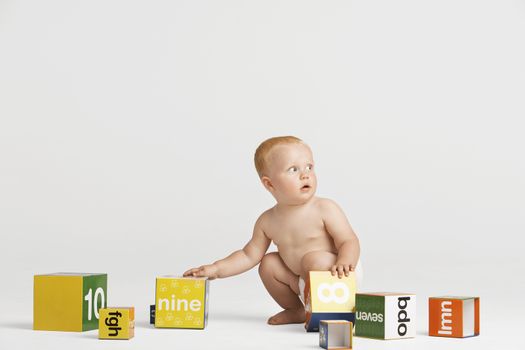 Full length of baby playing with building blocks isolated on white background