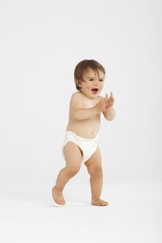 Full length of excited baby girl taking first step on white background