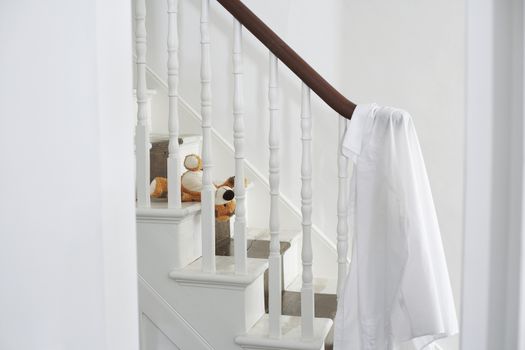 White shirt hanging on banisters with soft toy on steps