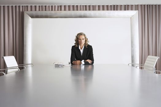 Portrait of serious female business executive sitting alone in boardroom