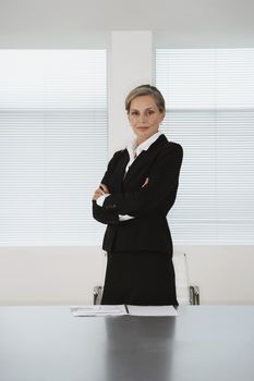 Portrait of confident middle aged businesswoman standing at conference table
