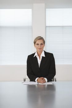 Portrait of confident middle aged businesswoman sitting at conference table