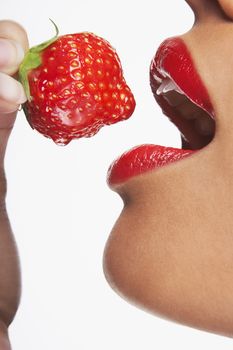 Detailed image of seductive woman eating strawberry on white background
