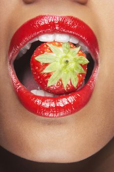Seductive woman with red lips eating strawberry