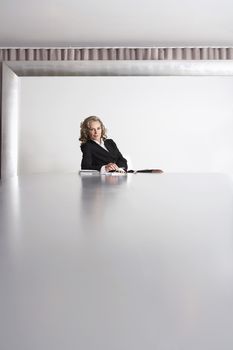 Portrait of confident female business executive sitting alone in boardroom
