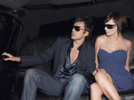 Young glamorous couple wearing sunglasses in limousine