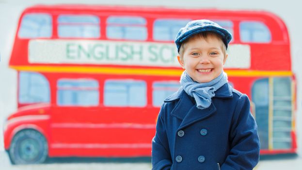 Little detective. Funny boy looking at the camera and standing near english schoolbus