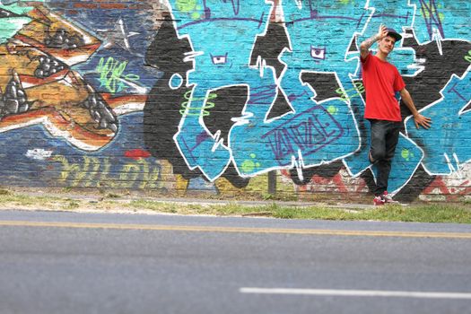 A greeting young Rapper greeting in front of a Graffiti wall.