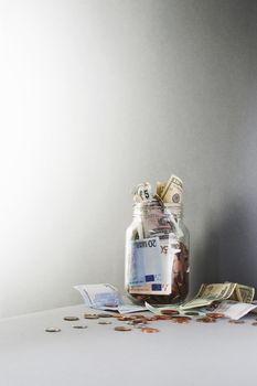 Notes and coins overflowing from jar