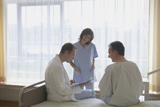 Doctor and nurse communicating with patient in hospital room