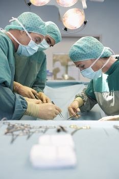 Side view of three surgeons at work in the operating theatre