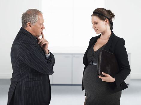 Boss talking to pregnant businesswoman half length