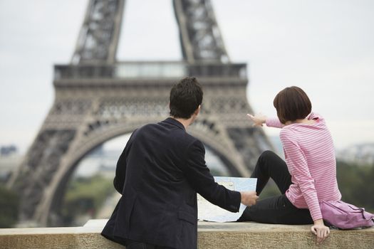 Rear view of a couple with map in front of Eiffel Tower