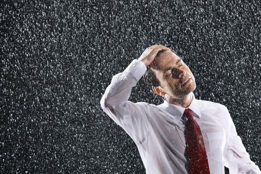 Businessman with hand on wet hair and eyes closed in the rain