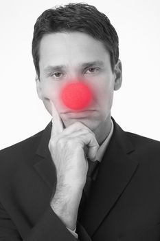 Portrait of a sad businessman wearing clown nose on white background