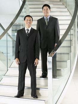 Full length portrait of two confident businessmen standing on stairs