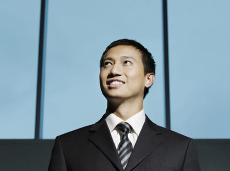 Smiling confident young businessman looking up