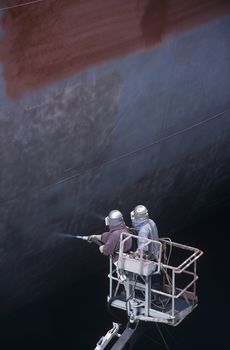 Two People standing in crane bucket Painting Large Ship