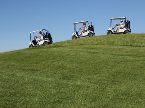Golfers driving carts in a row against clear blue sky