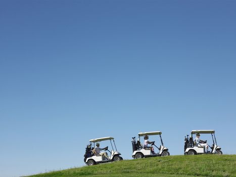 Golfers driving carts in a row against clear blue sky