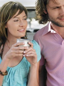 Woman drinking coffee from thermos cup standing next to man