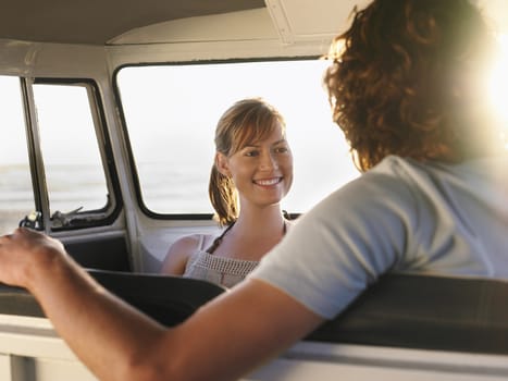 Smiling young woman looking at boyfriend in campervan