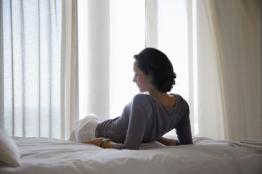 Woman reclining on bed in bedroom