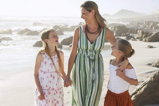 Happy woman and daughters communicating while standing at beach