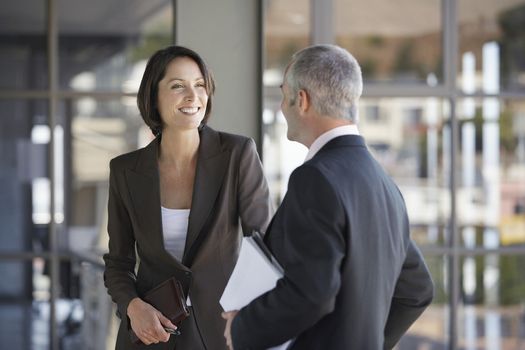 Happy businesswoman and businessman talking in office