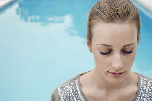 Young woman with eyes closed relaxing by swimming pool