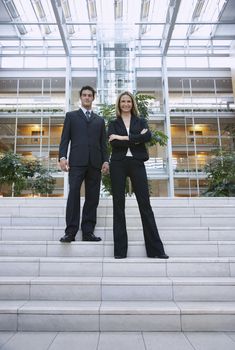 Full length portrait of two businesspeople standing outside office