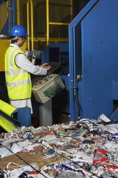 Man operating conveyor belt in recycling factory side view