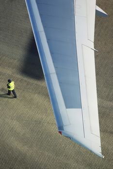 Man walking under airplane wing elevated view