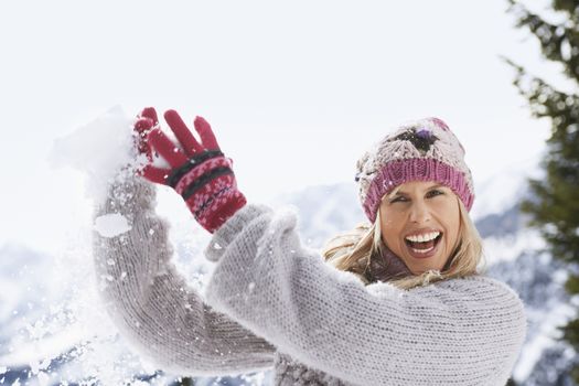 Portrait of a cheerful young woman catching snowball