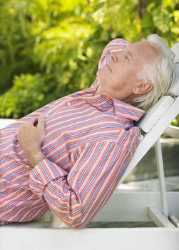 Side view of a mature man reclining on lounge chair outdoors