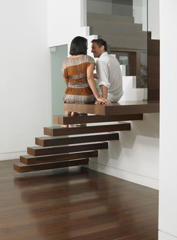 Rear view of a young couple sitting on stairs in house
