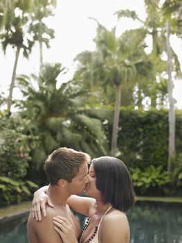 Side view of a young couple kissing in the garden