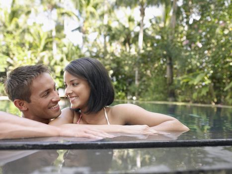 Happy young couple looking at each other in swimming pool