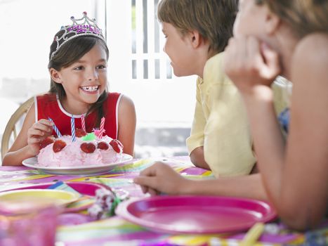 Young girl with birthday cake talking to guests at outdoor birthday party