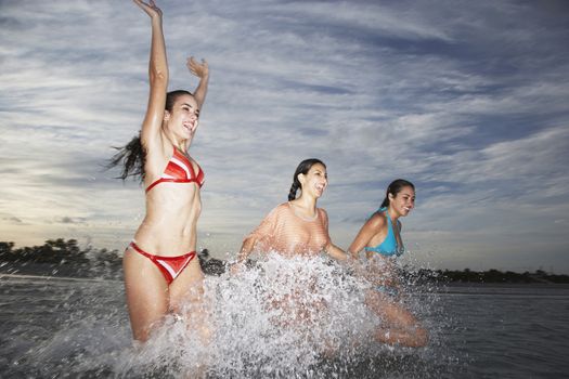 Three teenage girls splashing in sea during beach vacation