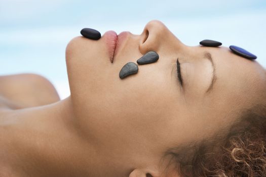 Woman receiving hot stone therapy head and shoulders close-up