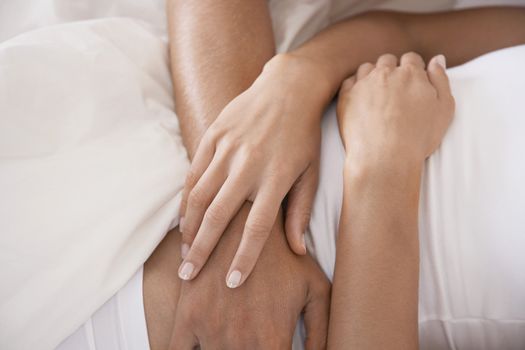 Midsection of couple embracing in bed