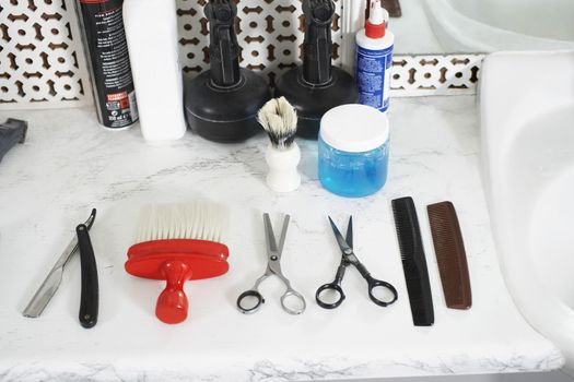 Scissors, combs, razor and brush on counter in barber shop
