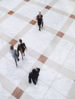 Elevated view of blurred business people walking on tiled floor
